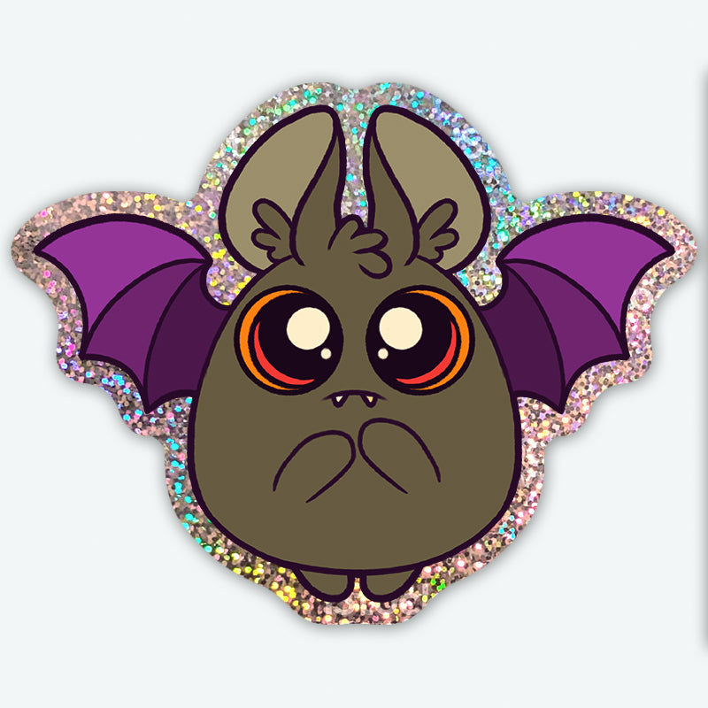 The Dark Glitter Bat Sticker from Bindlewood Shop features a cute cartoon bat with big orange eyes, purple wings, a round body, sparkly glitter border, and a sweet surprised face—perfect for adding charm to your collection.