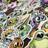 The ULTRA MEGA STICKER PACK! by Bindlewood Shop showcases a lively assortment of cute, big-eyed cartoon creatures—such as frogs, pumpkins, and quirky animals—all clustered together on a flat surface. These playful vinyl stickers are ideal for adding personality to your laptop, notebook, or water bottle.