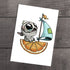 Vitamin Sea" Print by Chris Ryniak: a whimsical fine art print of a wide-eyed gray kitten sailing an orange-slice boat with a blue sail, on archival paper and set against a wooden background.