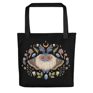 The Bindlewood Shop's Moth Magic Tote is a sturdy, weather-resistant bag featuring a vibrant symmetrical moth with large eyes, surrounded by mushrooms, leaves, crystals, acorns, and a crescent moon.