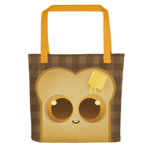 The Toast-Bag Tote from Bindlewood Shop is a durable bag with orange handles, featuring a cute cartoon toast with big eyes, a melting butter pat, and a smiling mouth on a dark brown plaid background.