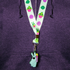 A person in a purple zip-up hoodie wears a Bindlewood Shop Succulent Lanyard, decorated with cartoon succulents and finished with a keychain of a blue bunny holding a pink cactus.