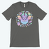 The Pastel Candy Bat Tee from Bindlewood Shop showcases a whimsical illustration of a bat-like creature with colorful wings, surrounded by stars, flowers, and two pastel ghosts on a charcoal-gray t-shirt. Made from pre-shrunk fabric, this vibrant and playful design exudes a mystical vibe with its gender-neutral fit.