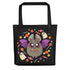 The Candy Bat Tote by Bindlewood Shop is a black, durable bag featuring a cute bat with purple wings, candy, stars, and ghosts—a festive Halloween accessory perfect for trick-or-treating and collecting sweets.