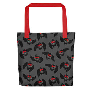 A dark gray tote bag made of durable fabric features a pattern of black cartoon owls with red eyes and beaks. The Mothman Cryptid Tote by Bindlewood Shop, ideal for cryptid-hunting paraphanalia or as a quirky Mothman tote bag, has bright red handles that create a striking contrast with the dark background and design.