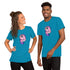 Two people smile side by side in Bindlewood Shop’s Flooficorn Tee, a lightweight shirt featuring a cute cartoon pink and purple cat-unicorn design on bright blue fabric.