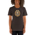 A woman smiling and wearing a dark t-shirt featuring a unique Thimblestump Hollow graphic print, designed by Chris Ryniak and Amanda Spayd, on the front. The t-shirt is "The Maker" Tee by Bindlewood Shop.