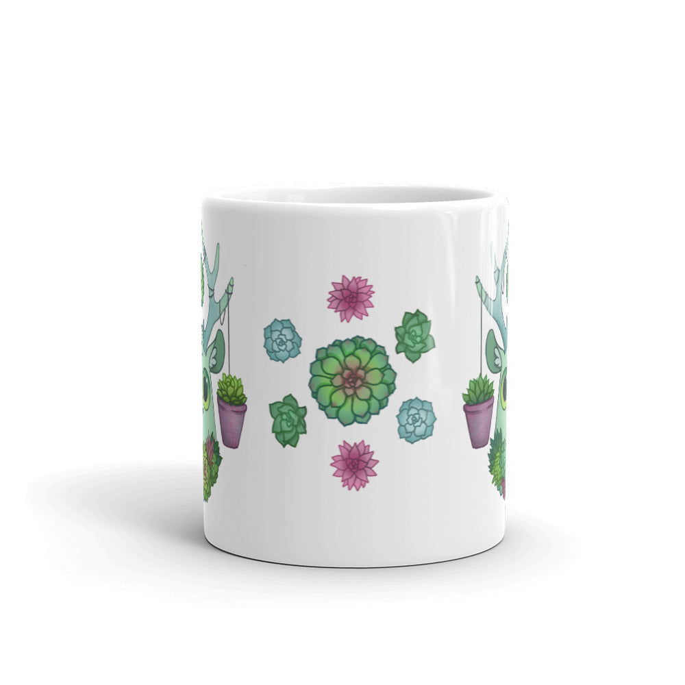 The Succulent Mug by Bindlewood Shop features a vibrant design of green and pink succulents symmetrically arranged and flanked by two potted plants. This dishwasher-safe mug boasts a crisp white ceramic background, blending style with convenience perfectly.